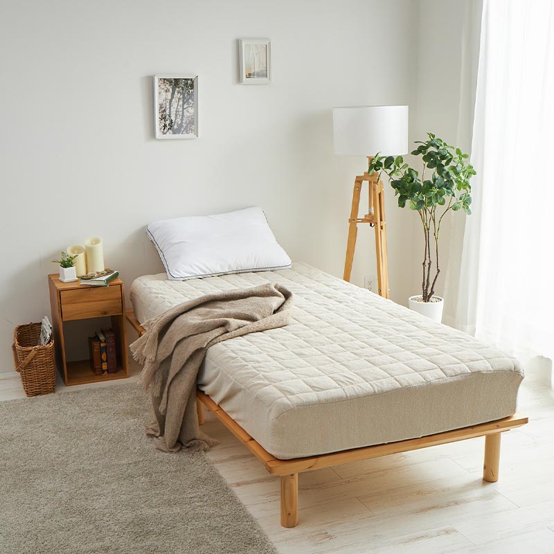 ナチュラルな雰囲気の寝室にシアーベージュのパッドシーツを敷いた様子